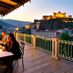Tbilisi Boutique Hotel Terrace**

"A charming boutique hotel in Tbilisi's Old Town, Georgia, featuring traditional Georgian architecture. The hotel terrace overlooks the Kura River and the illuminated Narikala Fortress at sunset. Guests are enjoying local treats like pkhali and churchkhela."

**